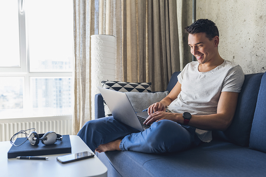 Homem sentado no sofá com notebook no colo